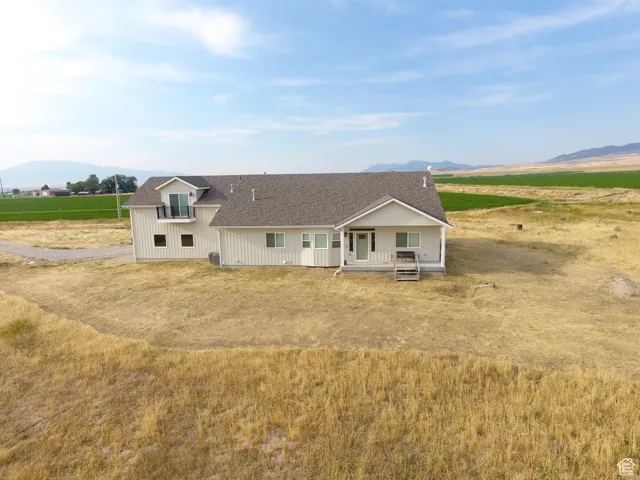 View of front of home featuring a mountain view, a shingled roof, a rural view, and a porch