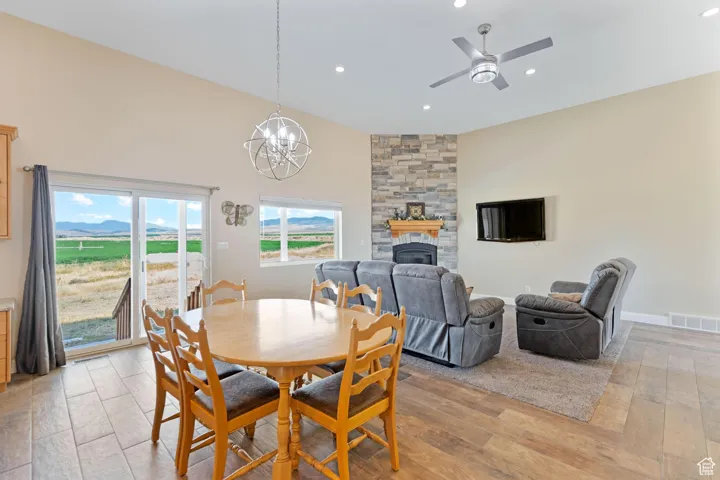 Dining space featuring light wood-type flooring, a fireplace, a chandelier, ceiling fan, and recessed lighting