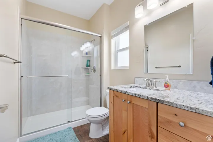 Second full bath featuring vanity, a stall shower, and dark wood-style flooring