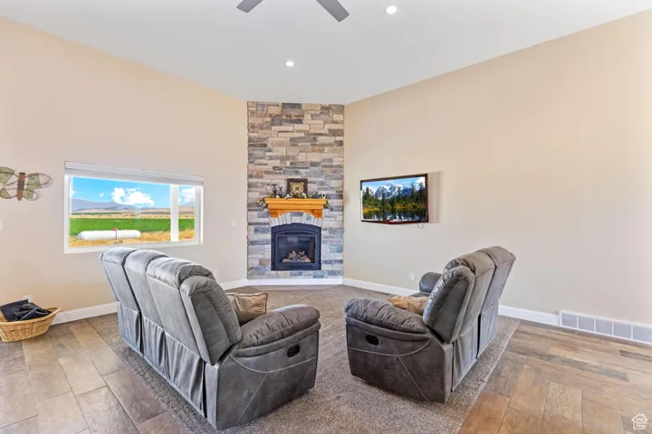 Living room featuring a stone fireplace, wood finished floors, and recessed lighting