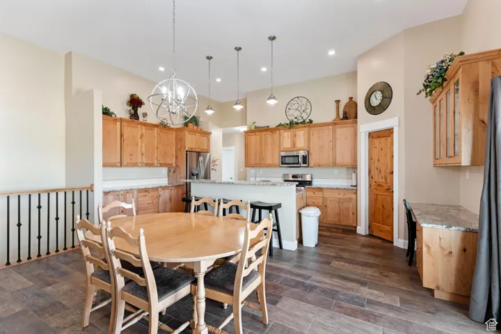 Dining room with a chandelier, dark wood-style flooring, a high ceiling, and recessed lighting