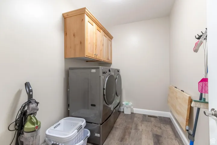Washroom with wood finished floors, washing machine and dryer, and cabinet space