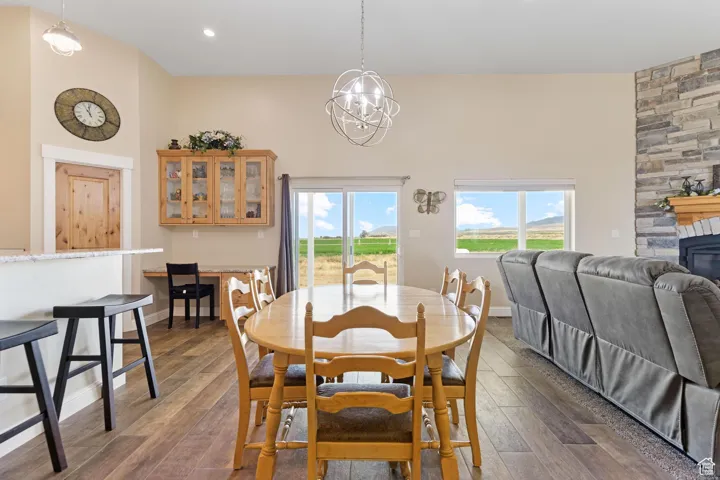 Dining space featuring dark wood-style floors, a fireplace, a chandelier, and a high ceiling
