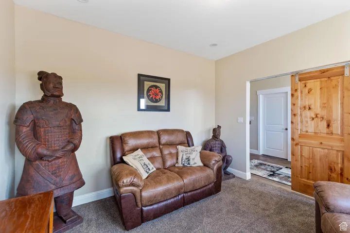 Carpeted living room featuring baseboards and a barn door