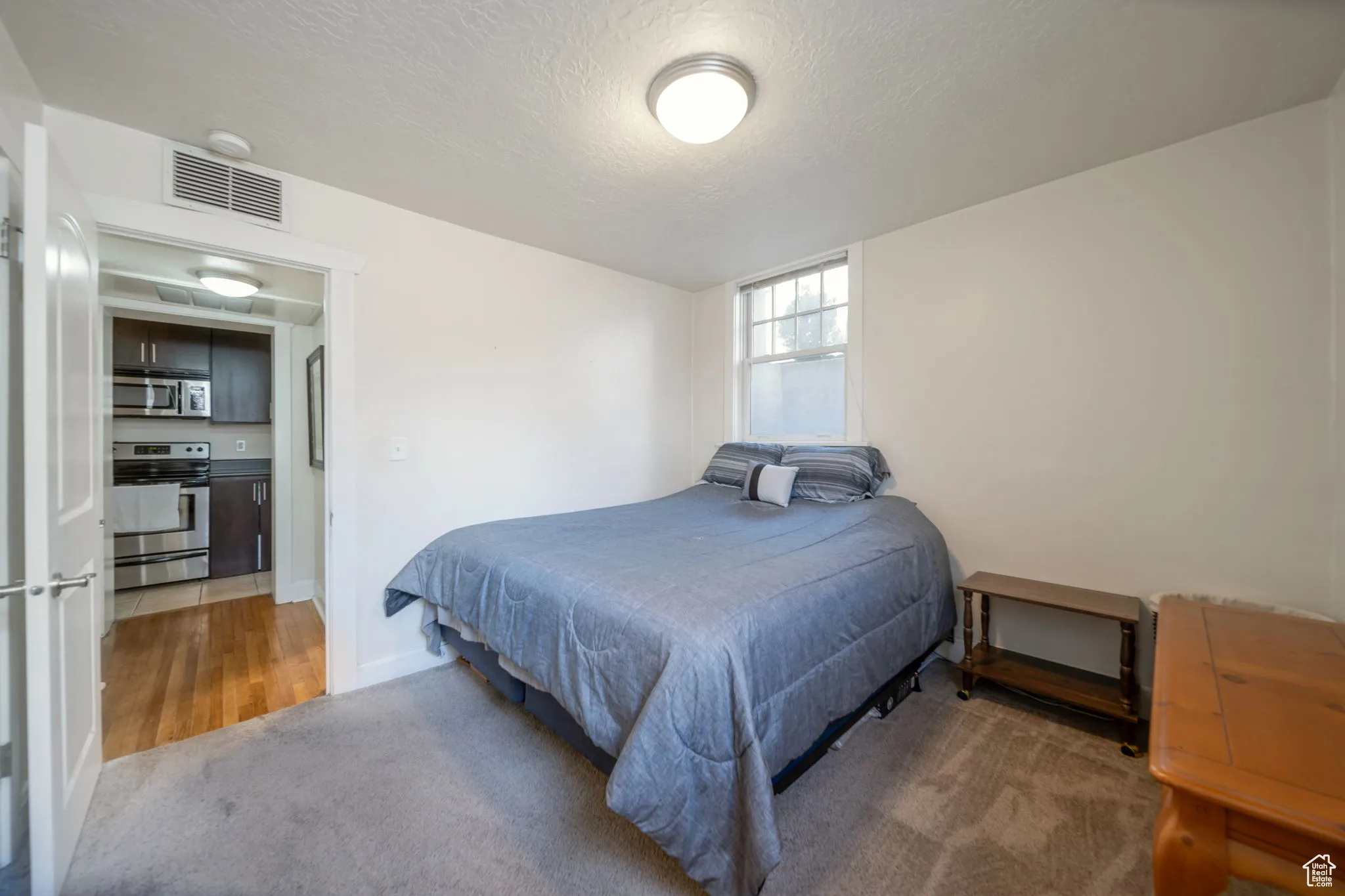Bedroom with light carpet and a textured ceiling