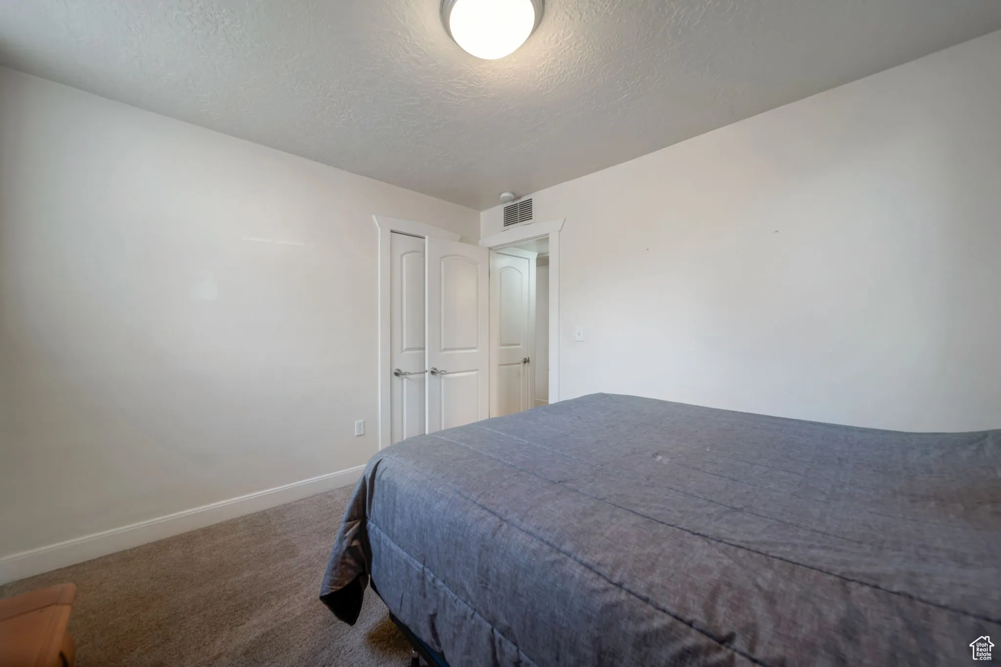 Carpeted bedroom featuring baseboards and a textured ceiling