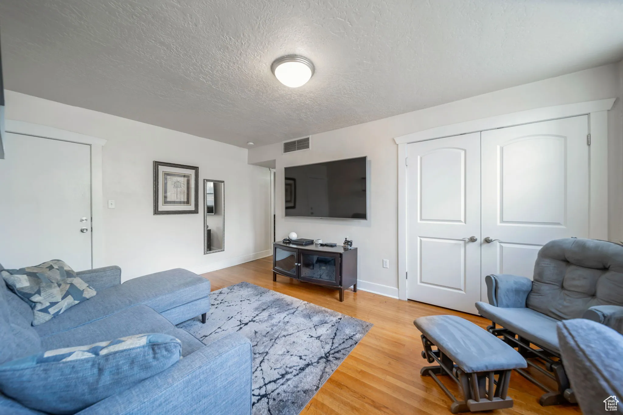 Living area featuring light wood-style floors and a textured ceiling