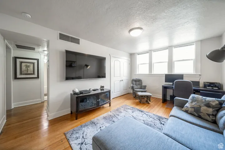 Living area featuring light wood-style flooring and a textured ceiling