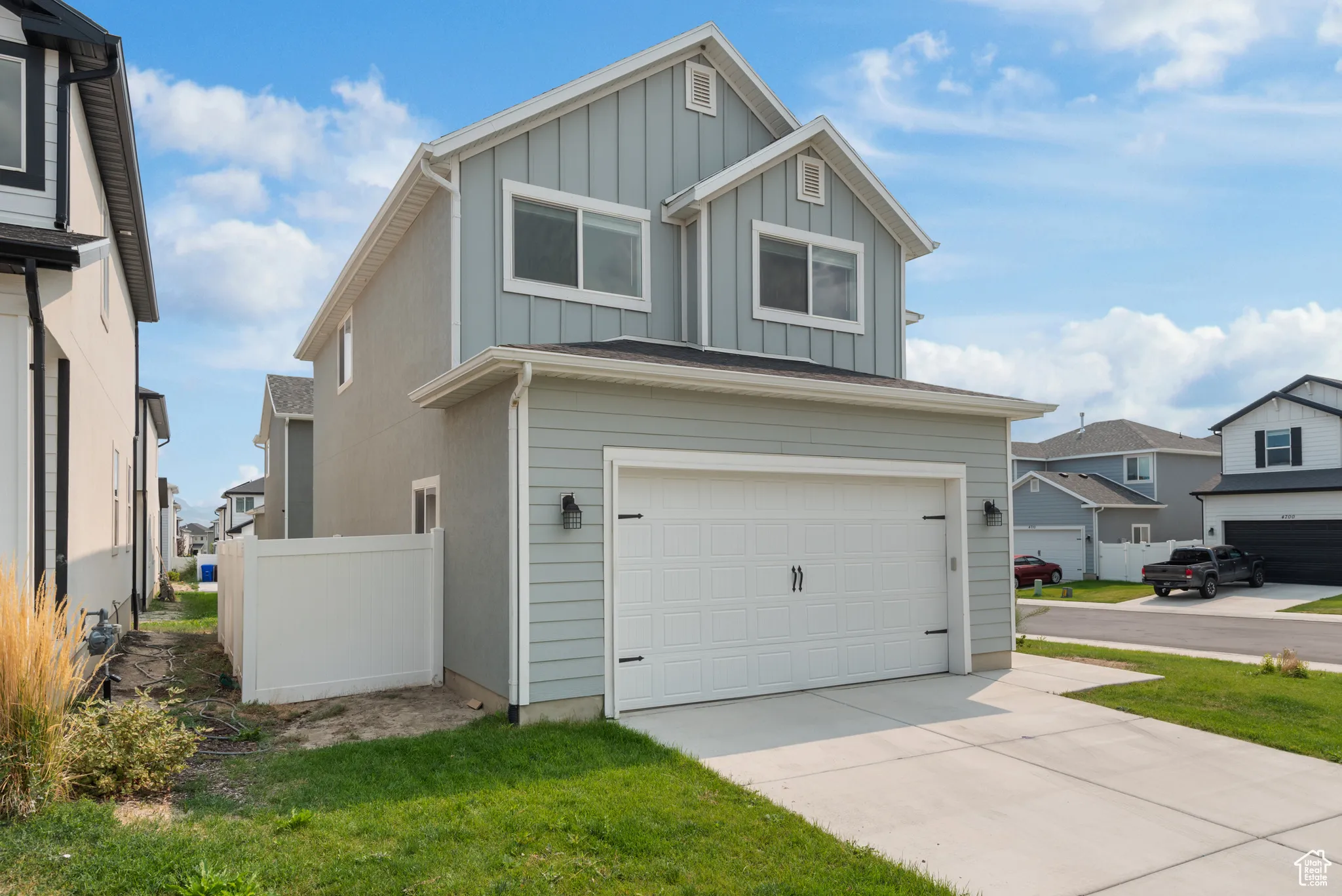 View of front of home featuring an attached garage, board and batten siding, driveway, and a residential view