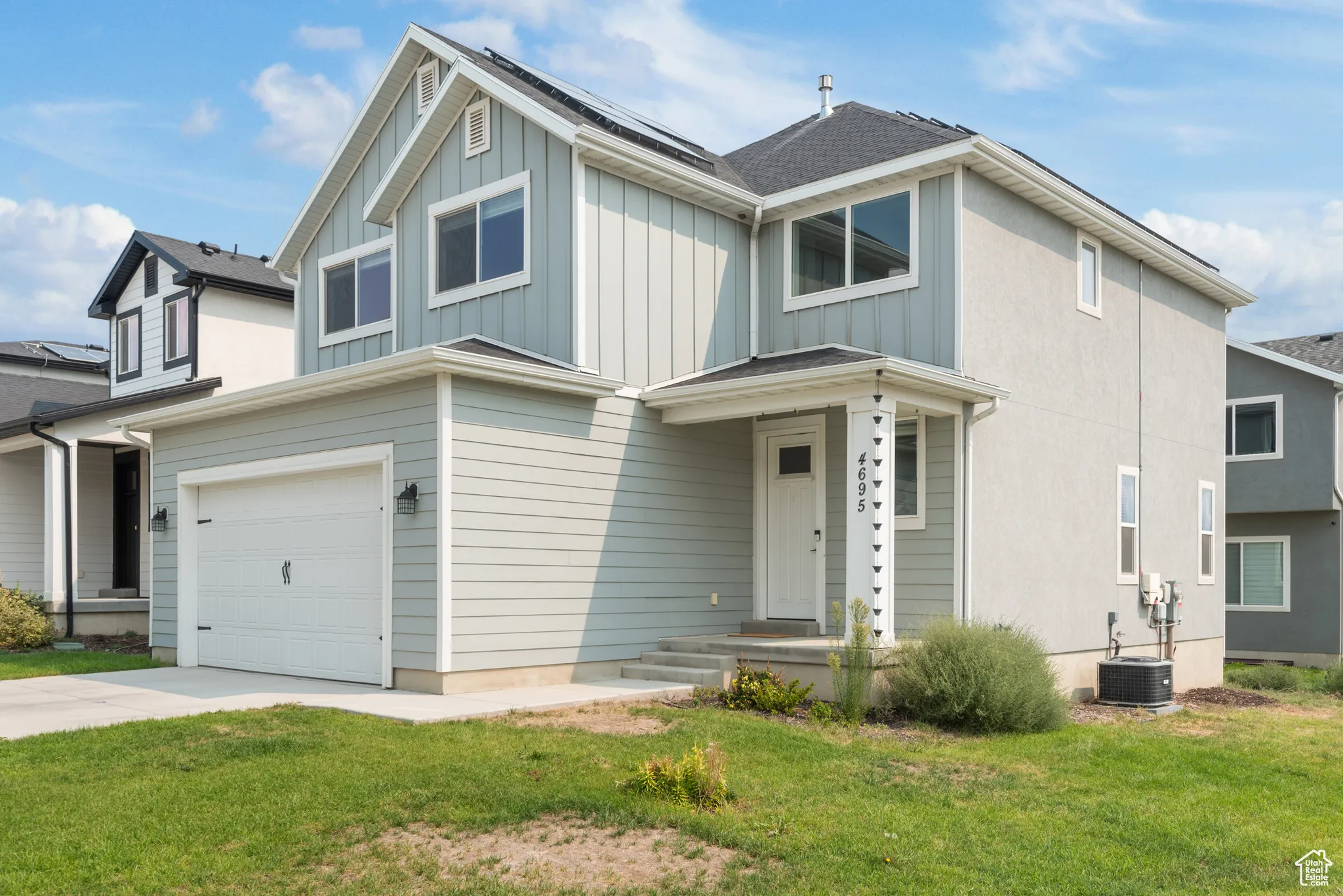 View of front of house featuring board and batten siding, a front lawn, a garage, and driveway