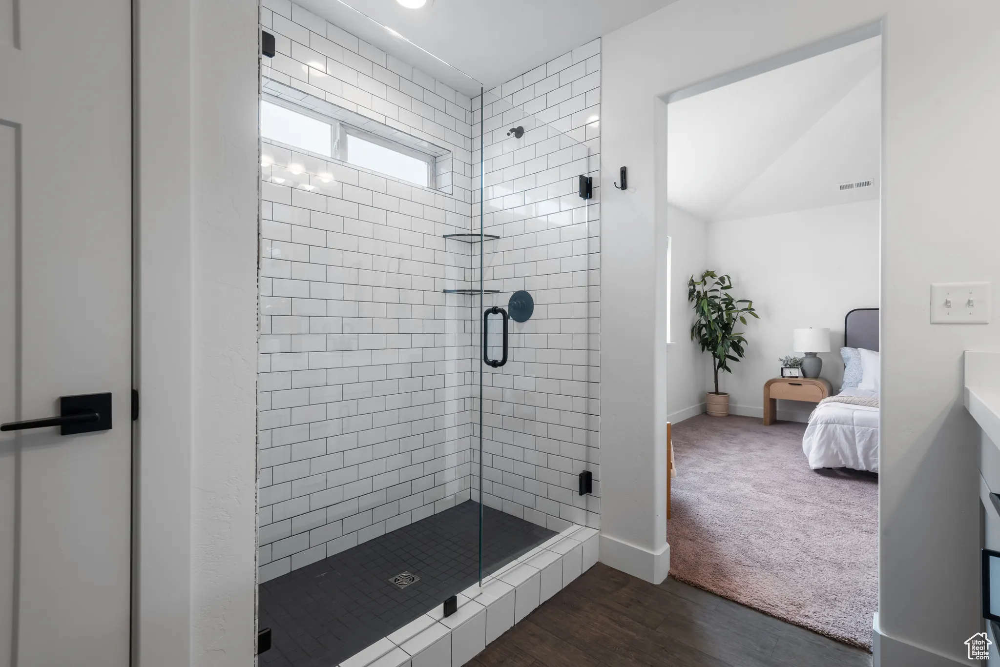 Ensuite bathroom featuring a stall shower and dark wood-style floors