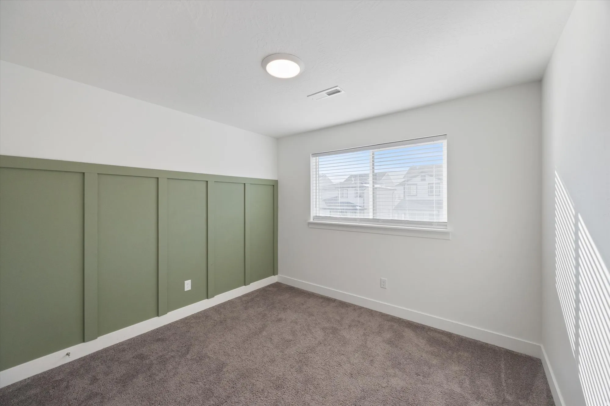 Spare room with a decorative wall, dark carpet, and wainscoting