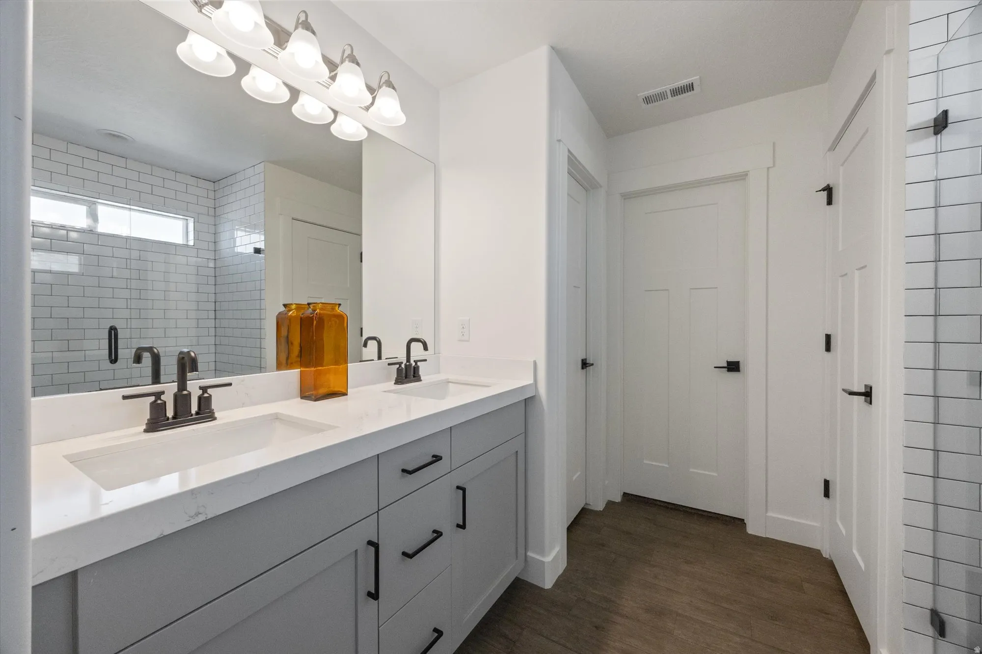 Bathroom featuring double vanity, a shower stall, and dark wood finished floors