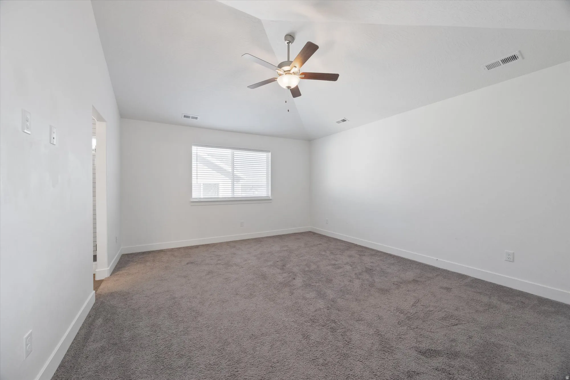 Carpeted spare room with lofted ceiling and a ceiling fan