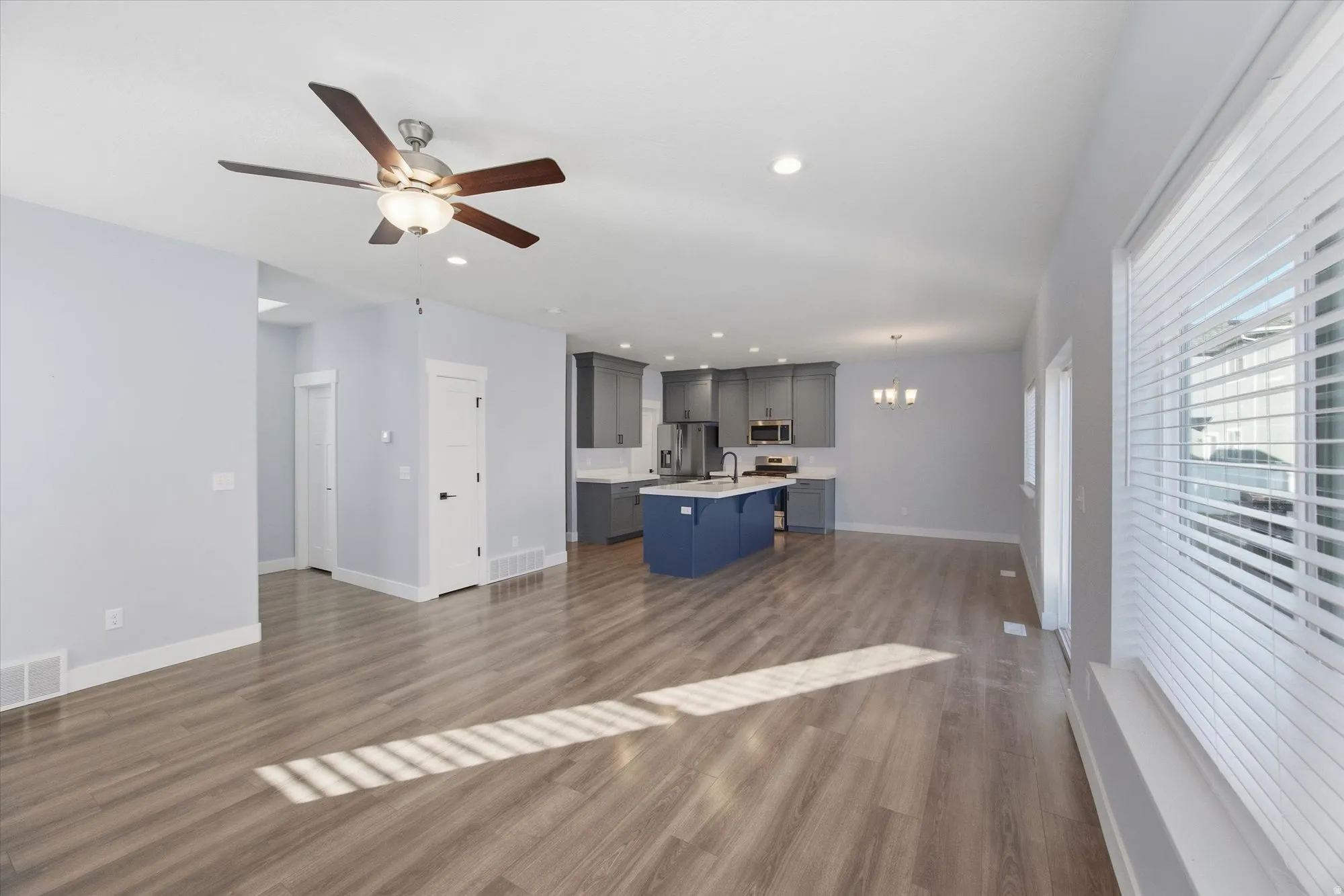 Unfurnished living room featuring dark wood-style floors, a chandelier, a ceiling fan, and recessed lighting