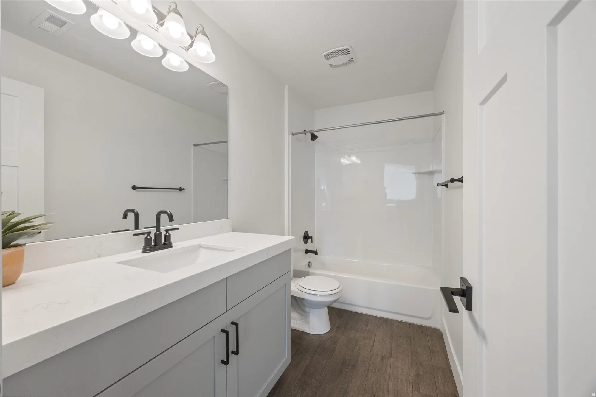 Bathroom featuring vanity, shower / tub combination, and dark wood-style floors