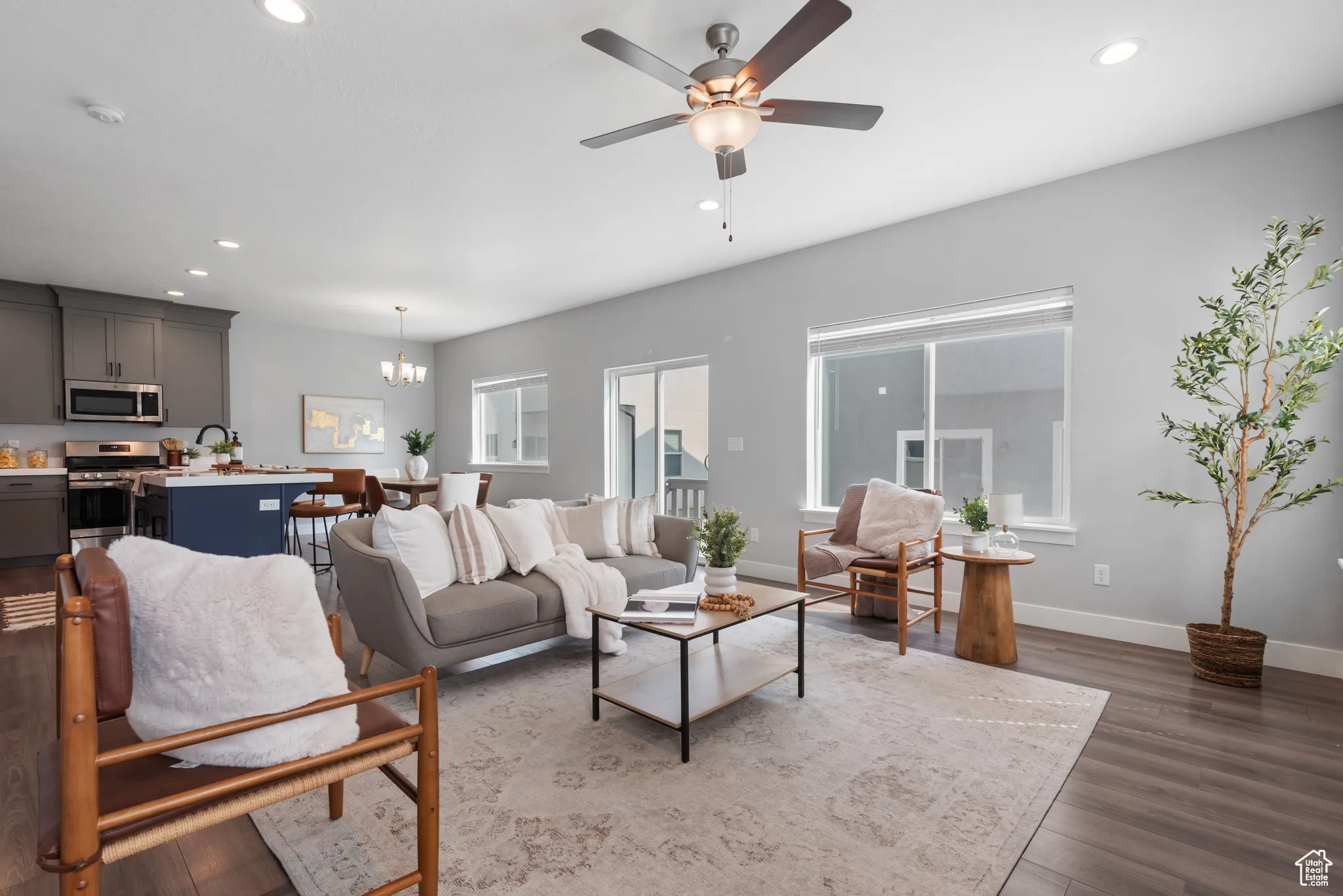 Living room with dark wood-style flooring, recessed lighting, ceiling fan, and a chandelier