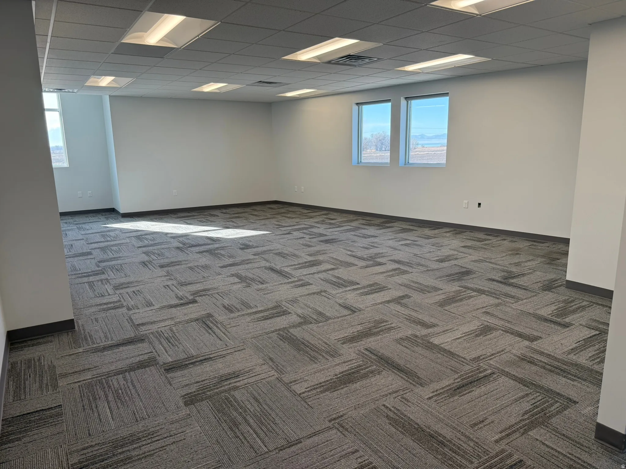 Unfurnished room with carpet and a drop ceiling