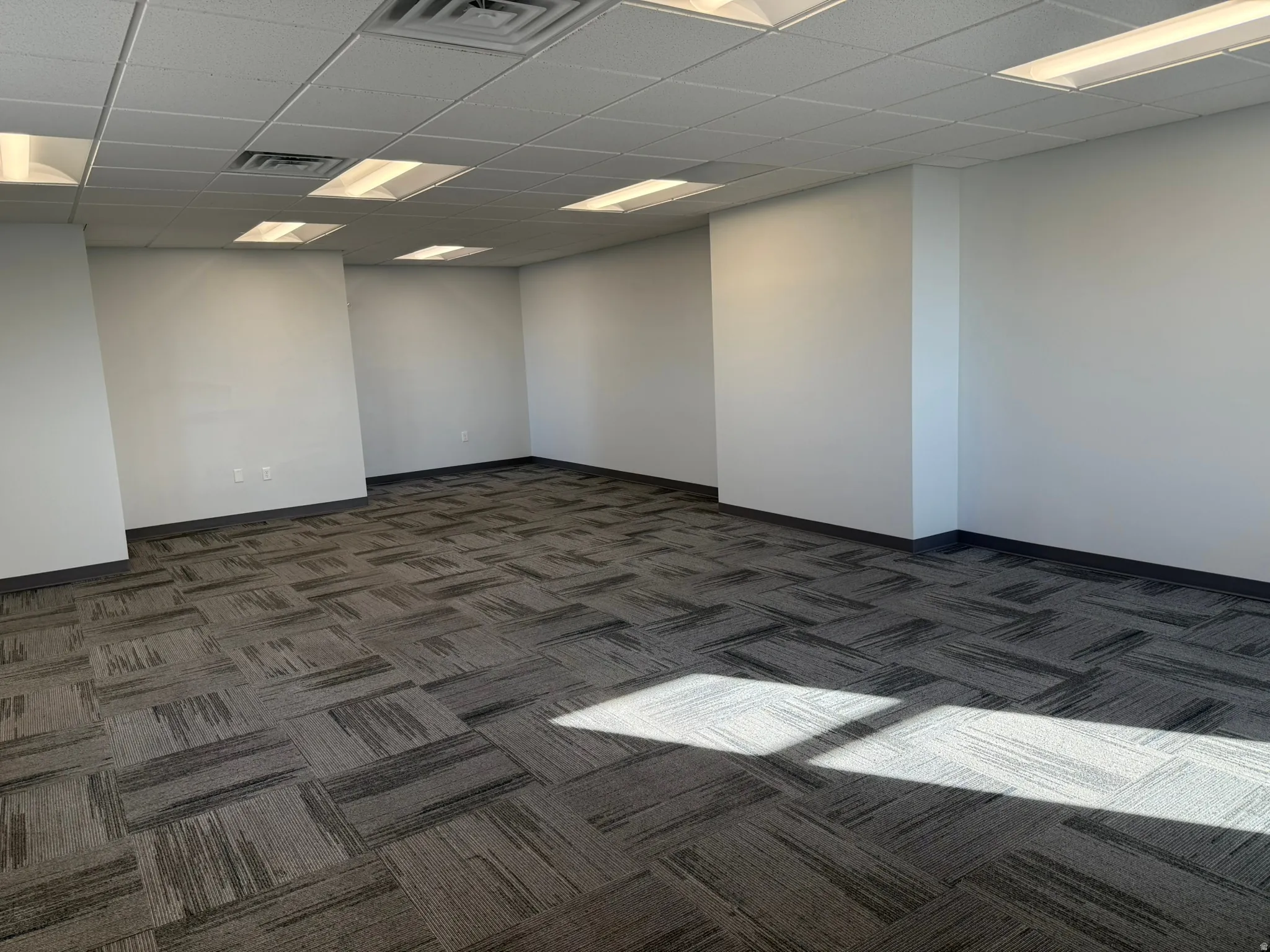 Unfurnished room featuring dark carpet and a paneled ceiling