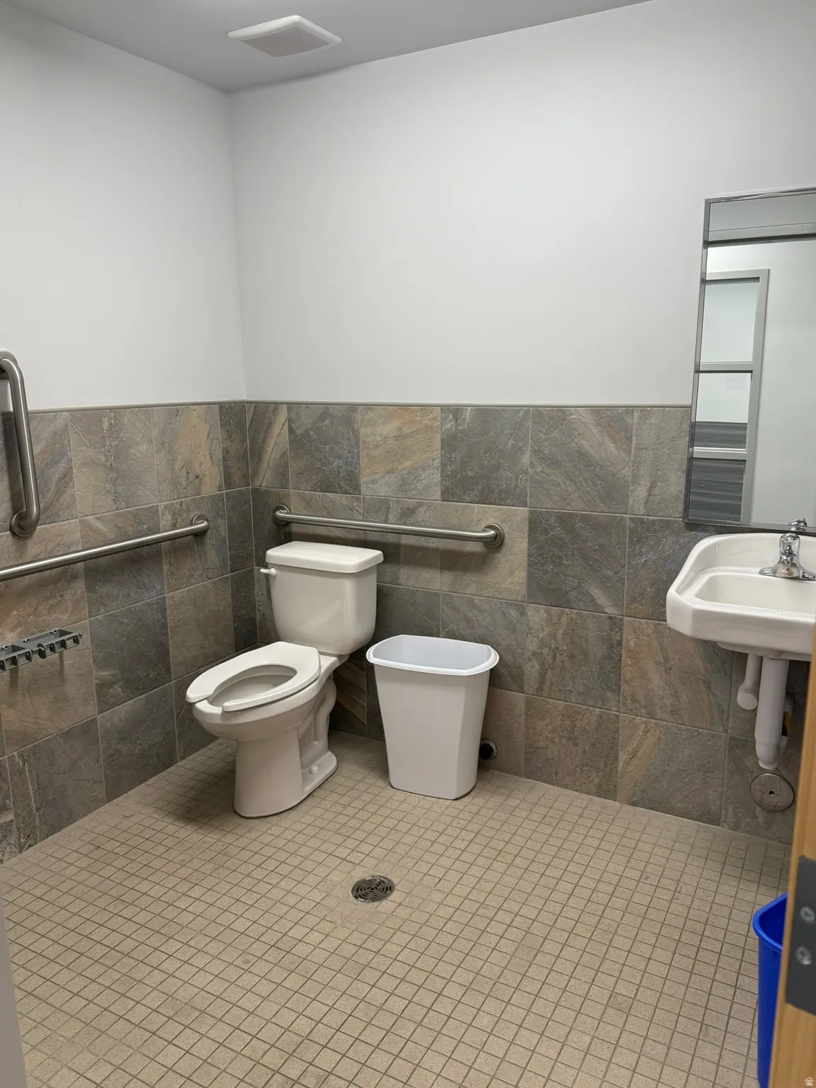Half bathroom featuring tile walls, a wainscoted wall, and tile patterned floors