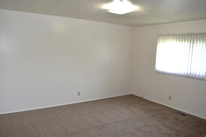 Carpeted empty room featuring a textured ceiling and baseboards