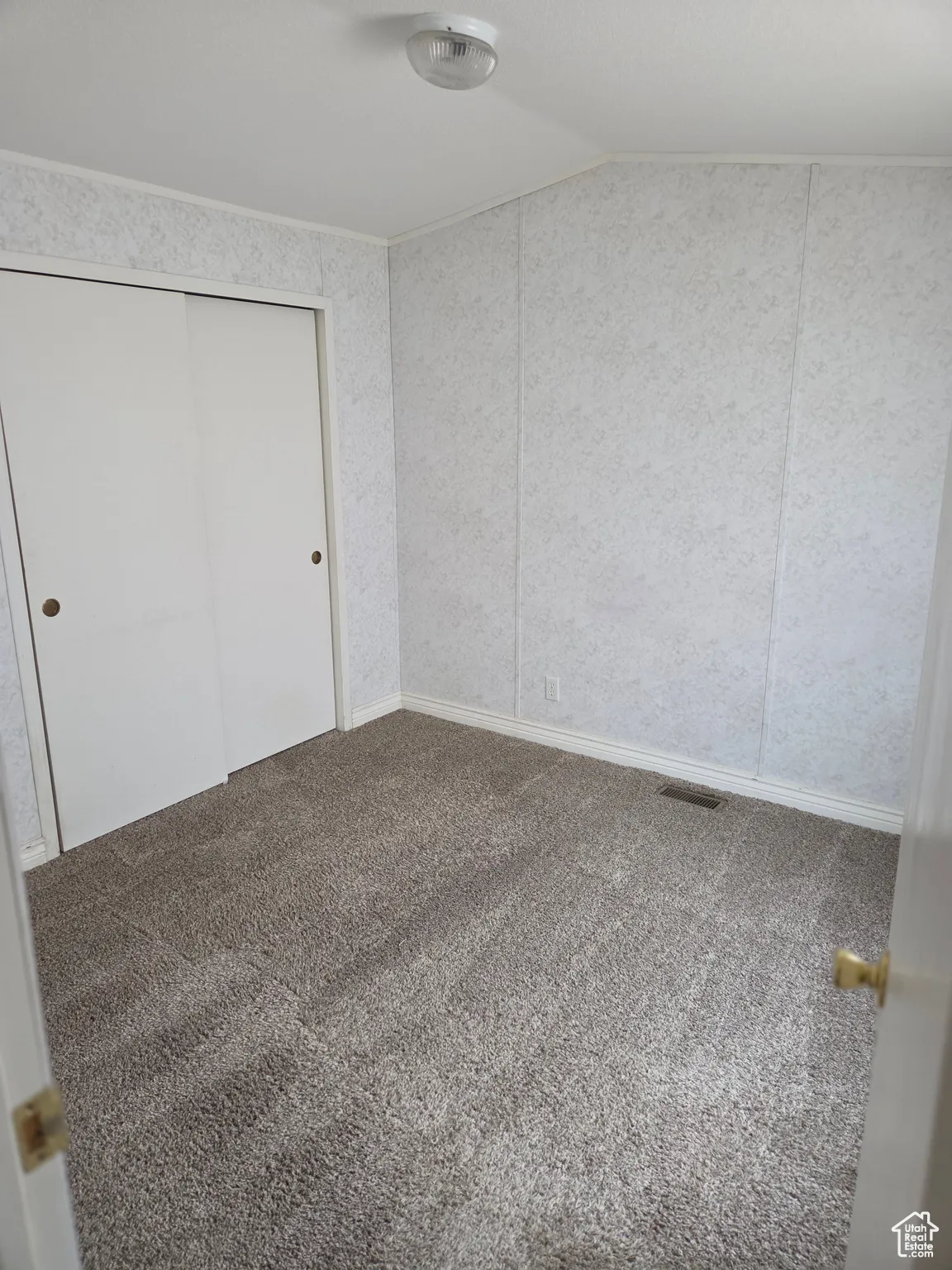 Unfurnished bedroom with carpet flooring, vaulted ceiling, and a closet