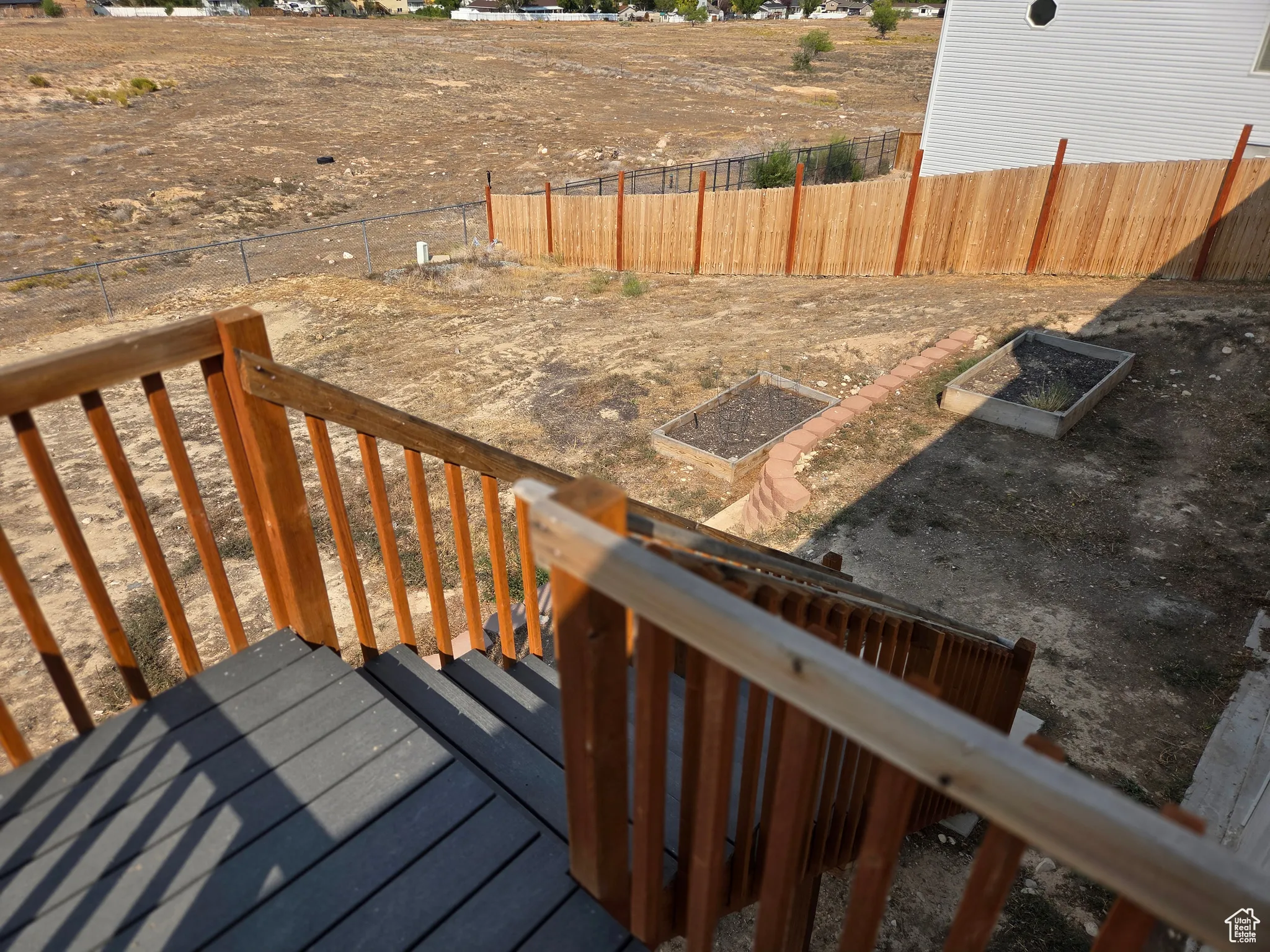 Wooden terrace with a fenced backyard and a garden