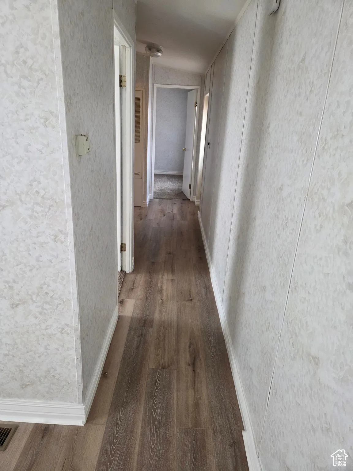 Corridor featuring dark wood-style floors and baseboards