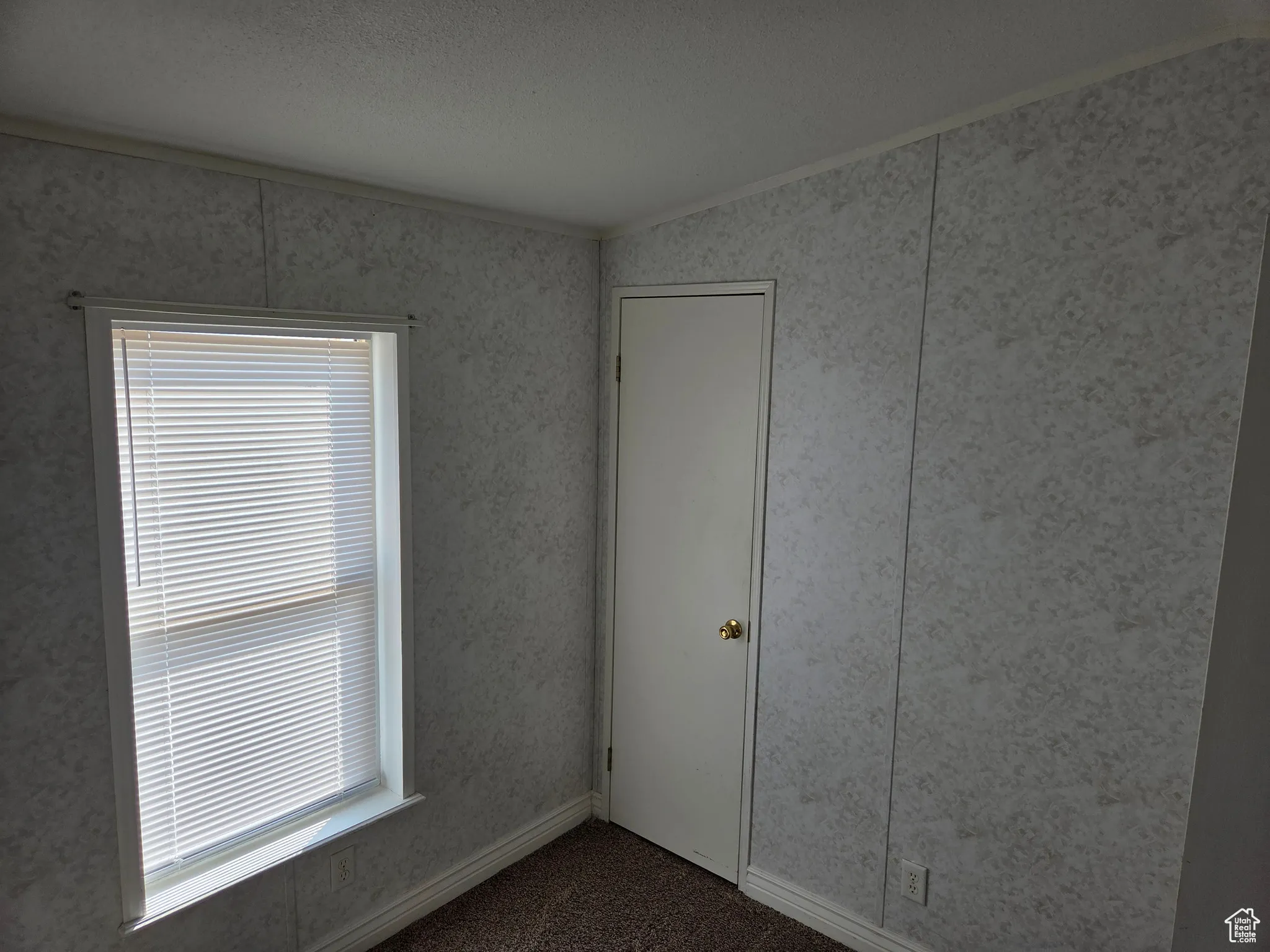 Carpeted empty room with ornamental molding, a textured ceiling, and wallpapered walls