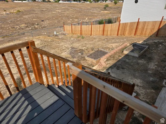 Wooden terrace with a fenced backyard and a garden