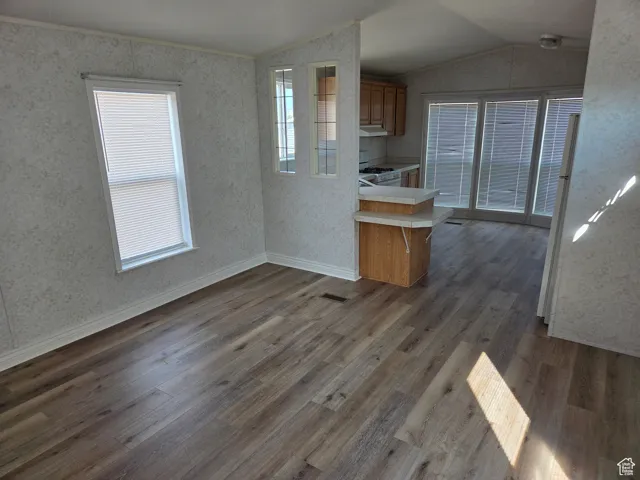 Kitchen featuring light countertops, white appliances, dark wood-type flooring, brown cabinets, and vaulted ceiling