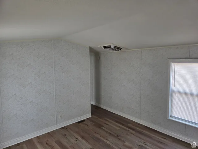 Unfurnished room featuring dark wood-style floors and vaulted ceiling