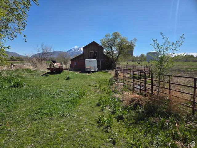 View of yard featuring a barn, an outdoor structure, a view of countryside, and a mountain view