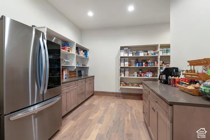 Kitchen with smart refrigerator, light wood-style floors, open shelves, brown cabinets, and dark stone counters