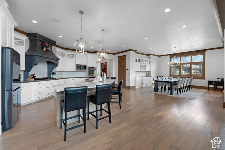 Kitchen featuring a chandelier, a center island with sink, hanging light fixtures, a breakfast bar area, and crown molding