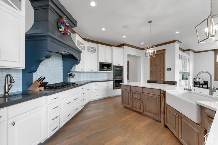 Kitchen with glass insert cabinets, dark wood-style flooring, hanging light fixtures, decorative backsplash, and dark stone counters