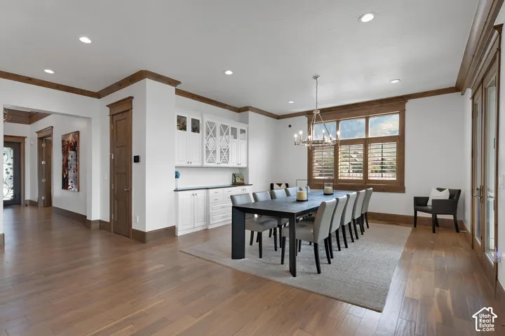 Dining space with crown molding, dark wood-style floors, recessed lighting, and a chandelier
