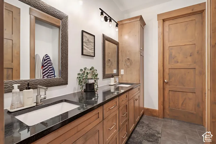 Bathroom with double vanity and dark tile patterned flooring