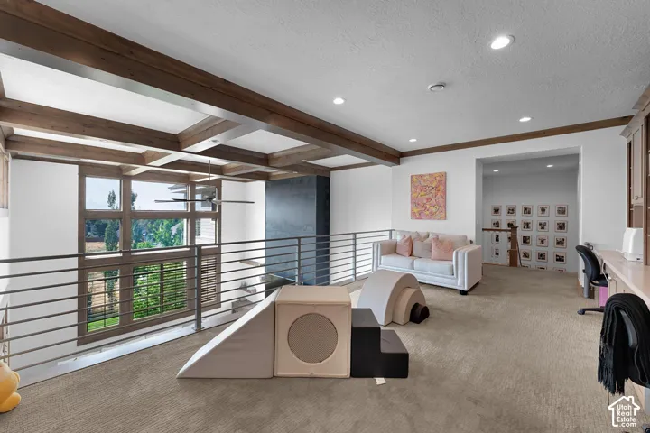 Carpeted living area with beamed ceiling, recessed lighting, and a textured ceiling
