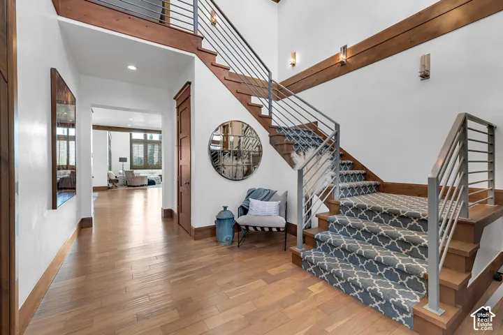 Stairway featuring wood finished floors, recessed lighting, and a high ceiling