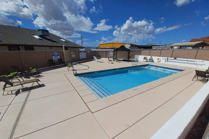 Outdoor swimming pool with integrated steps, surrounded by a concrete deck, and enclosed by fencing
