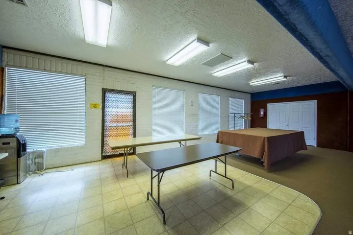 Recessed lighting, fluorescent lighting, and multiple windows illuminate this room featuring wall-to-wall carpeting and tile flooring