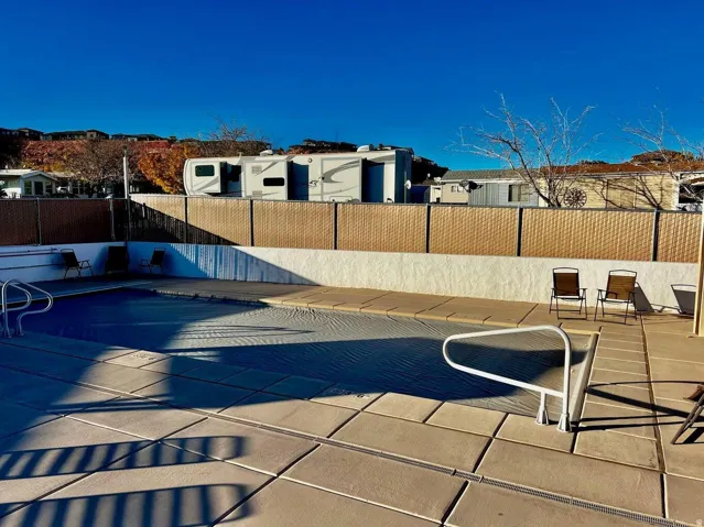 Outdoor pool area featuring a covered pool, surrounding concrete patio, and a privacy fence