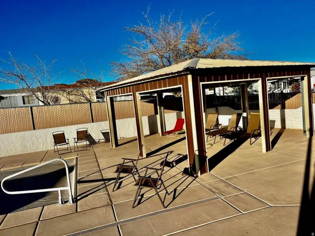 Expansive concrete patio area with a covered seating structure, featuring a metal roof and support columns