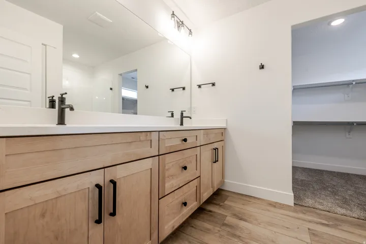 Bathroom with double vanity, a spacious closet, recessed lighting, and light wood-type flooring