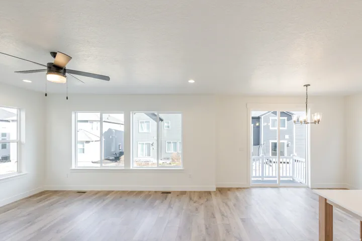 Unfurnished living room featuring light wood-type flooring, suspended lighting, ceiling fan, and a textured ceiling