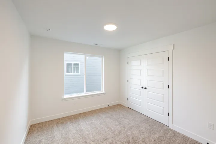 Unfurnished bedroom featuring light carpet and a closet