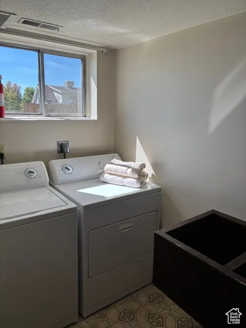 Washroom with washer and dryer and a textured ceiling