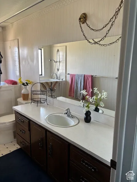 Bathroom with vanity, wallpapered walls, and light tile patterned flooring