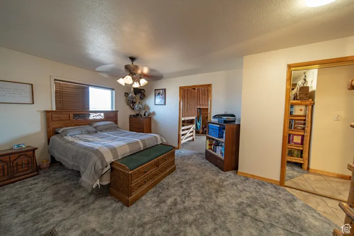 Bedroom featuring a textured ceiling, carpet flooring, and a ceiling fan